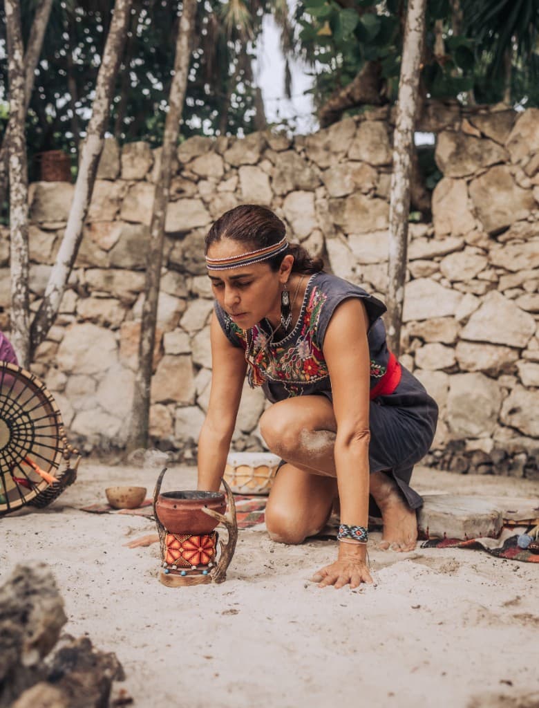 Woman kneeling at a ceremonial incense ritual outdoors