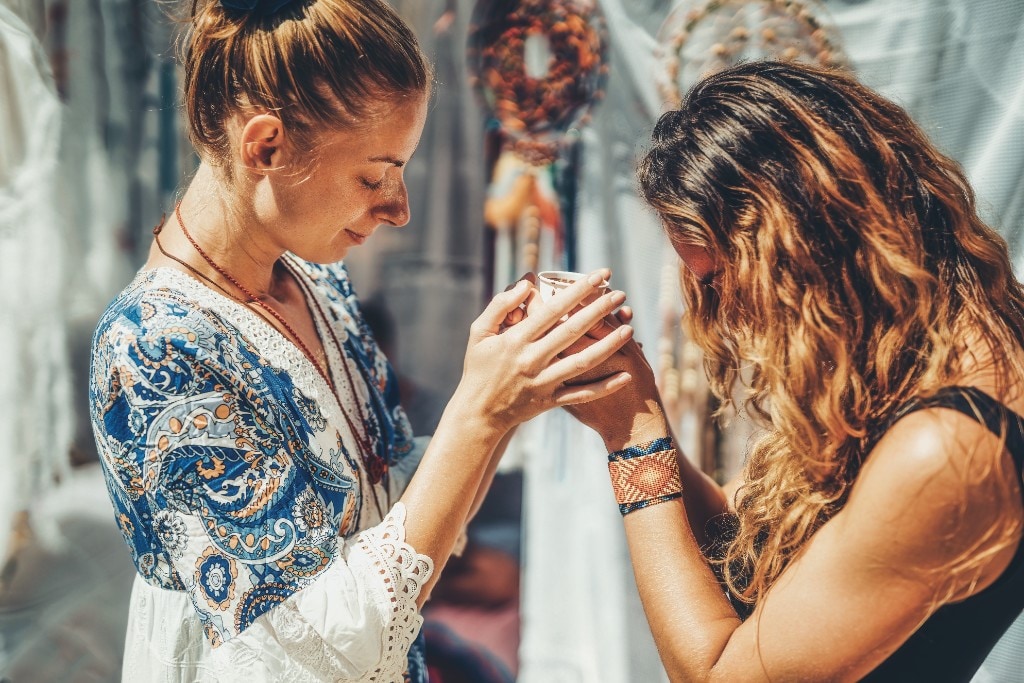 Cacao ceremony with cup passed between facilitator and guest