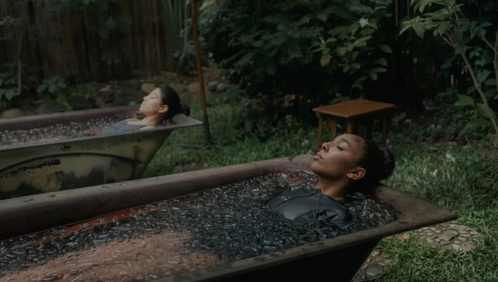 Two women in ice baths in a lush outdoor garden